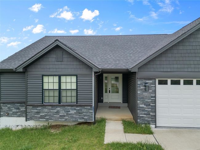 Doorway to property featuring an attached garage, roof with shingles, and stone siding | Image 6