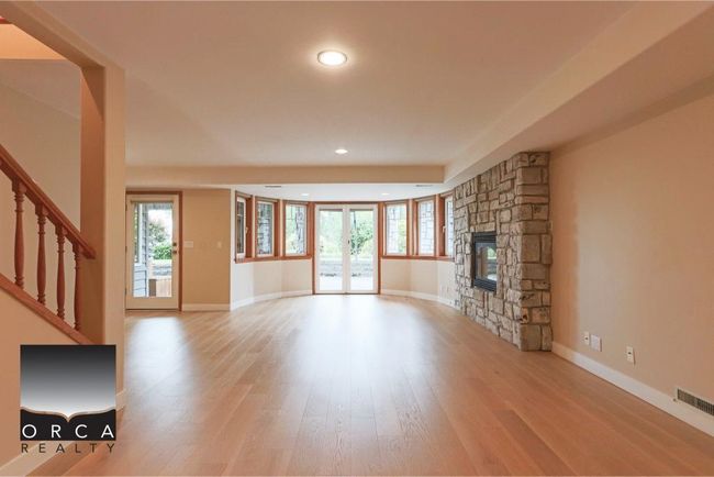 Unfurnished living room with a stone fireplace, wood finished floors, healthy amount of natural light, recessed lighting, and stairs | Image 37
