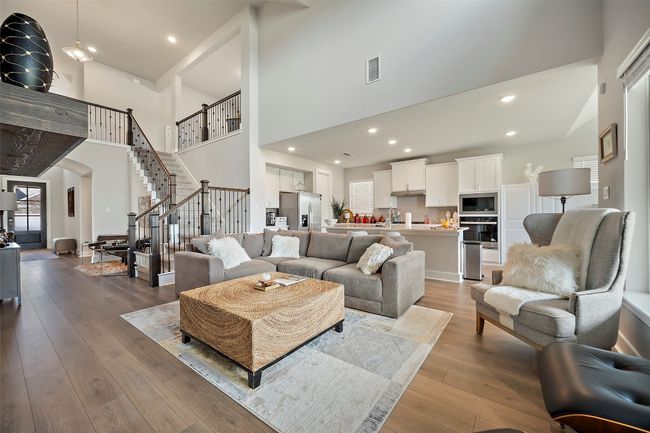 Living room featuring a towering ceiling, stairs, wood-type flooring, recessed lighting, and arched walkways | Image 15