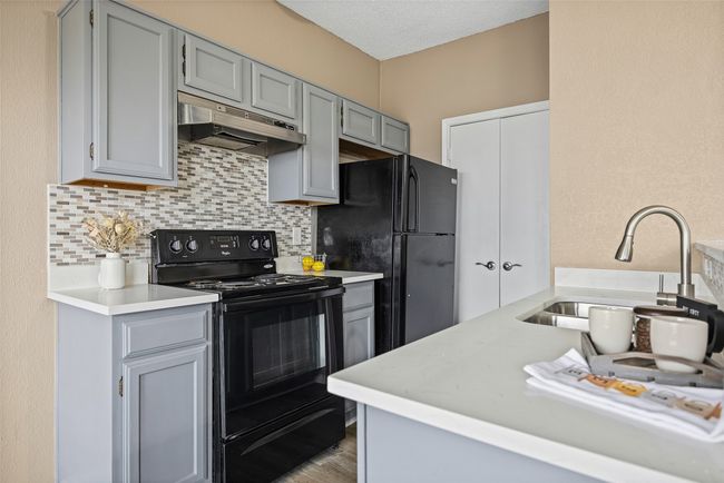 Kitchen featuring tasteful backsplash, sink, gray cabinetry, and black appliances | Image 4