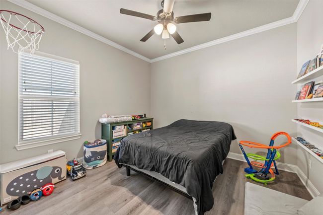 Bedroom featuring baseboards, crown molding, a ceiling fan, and wood finished floors | Image 14