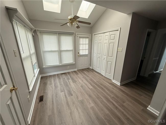 Unfurnished bedroom with a skylight, vaulted ceiling, wood finished floors, and multiple windows | Image 14