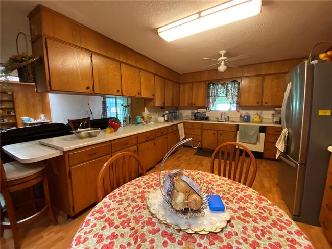 Kitchen featuring freestanding refrigerator, dishwasher, light wood-style floors, brown cabinets, and a sink | Image 7