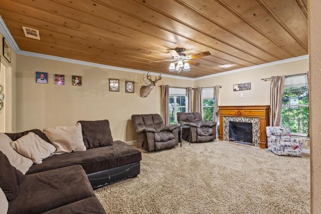 Living room with wooden ceiling, visible vents, carpet, and ornamental molding | Image 5