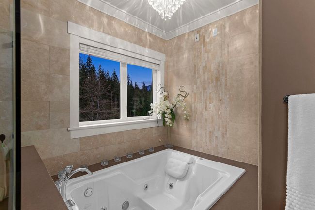 Bathroom with an inviting chandelier, a jetted tub, and tile walls | Image 25