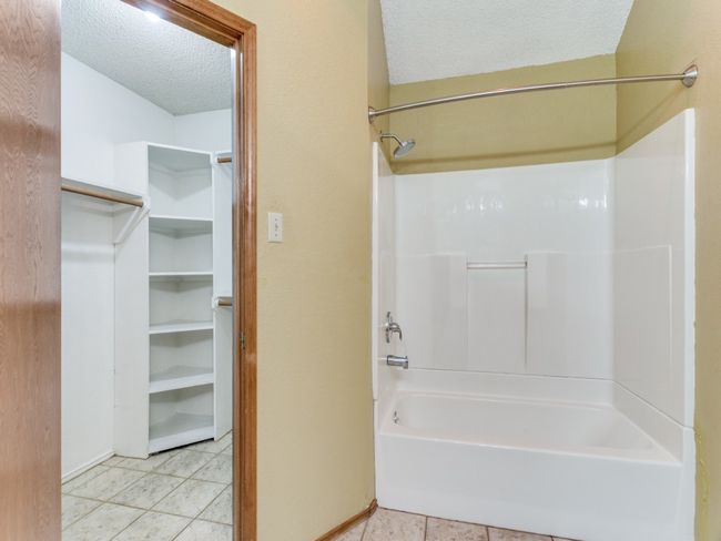 Full bathroom featuring a textured ceiling, tile patterned flooring, and washtub / shower combination | Image 19