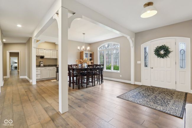 foyer entrance featuring baseboards, wood finished floors, and a notable chandelier | Image 6