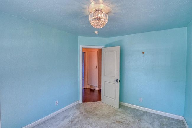 Unfurnished room featuring carpet floors, baseboards, a chandelier, and a textured ceiling | Image 18