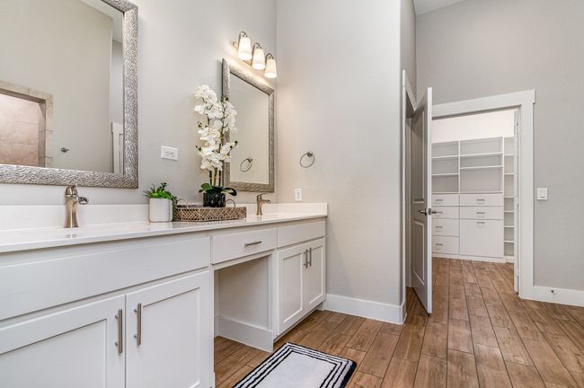 Primary Full bath with double vanity, wood finished floors, baseboards, and a spacious closet | Image 18