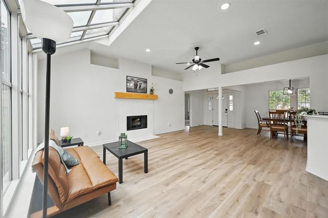 Living room with recessed lighting, a ceiling fan, a tiled fireplace, light wood finished floors, and baseboards | Image 6