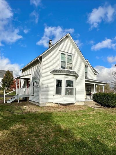 Frontal view of house with a porch and side entrance leading to upper unit | Image 3