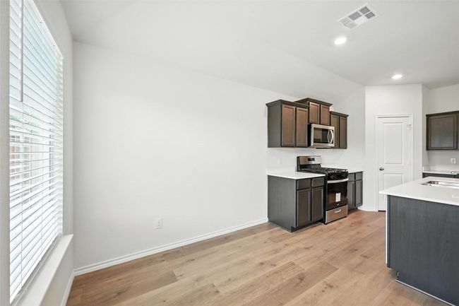 Kitchen featuring stainless steel appliances, light wood-style floors, recessed lighting, light countertops, and dark brown cabinets | Image 5