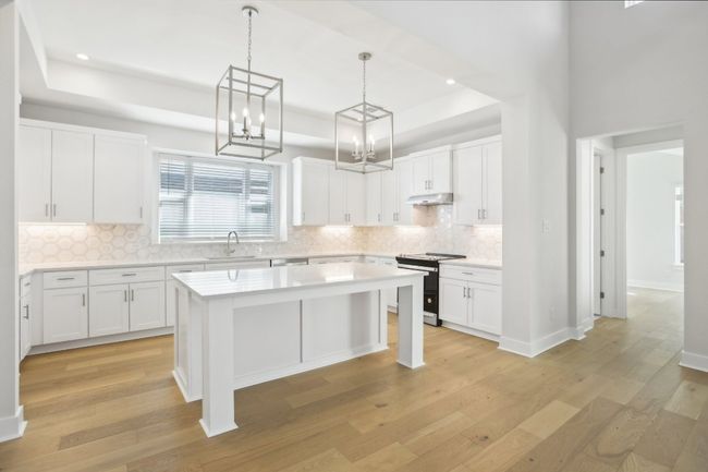 Kitchen featuring light countertops, range with electric stovetop, light wood-type flooring, and a sink | Image 13