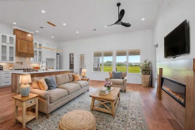 Step into a bright and inviting living space featuring an elegant open layout, cozy fireplace, and stunning views through expansive windows. Perfect for comfortable living and entertaining. DIGITALLY STAGED | Image 18