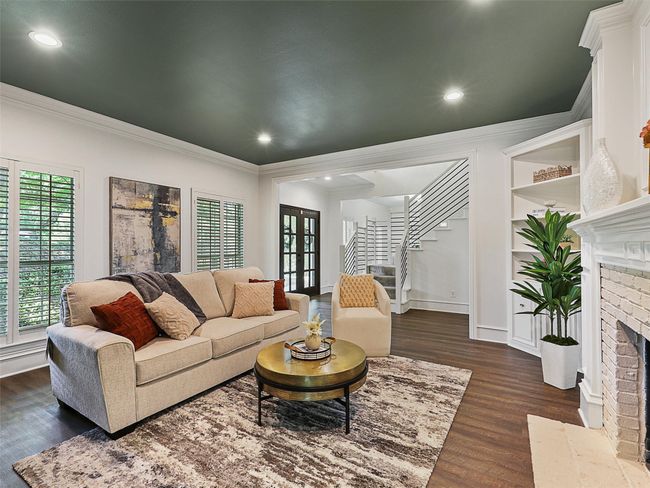 Living room featuring a fireplace, stairway, crown molding, and dark wood-style floors | Image 6