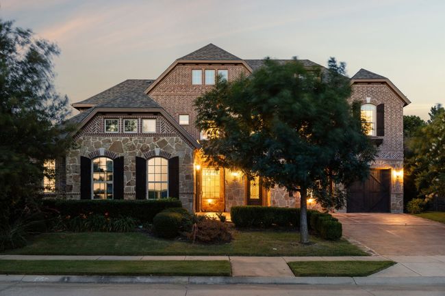 View of front of property featuring stone siding, a garage, driveway, and brick siding | Image 32