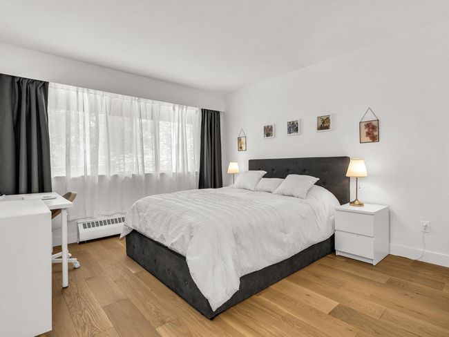 Bedroom with baseboard heating, wood finished floors, and baseboards | Image 19