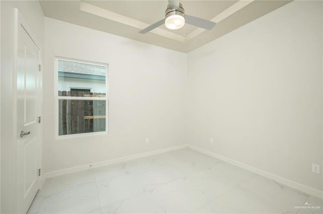 Spare room with baseboards, light marble finish floors, a ceiling fan, and a tray ceiling | Image 11