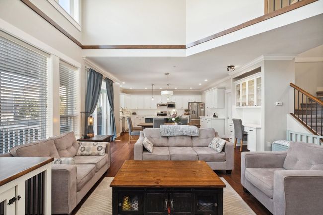Living area featuring crown molding, stairway, recessed lighting, a towering ceiling, and wood finished floors | Image 6