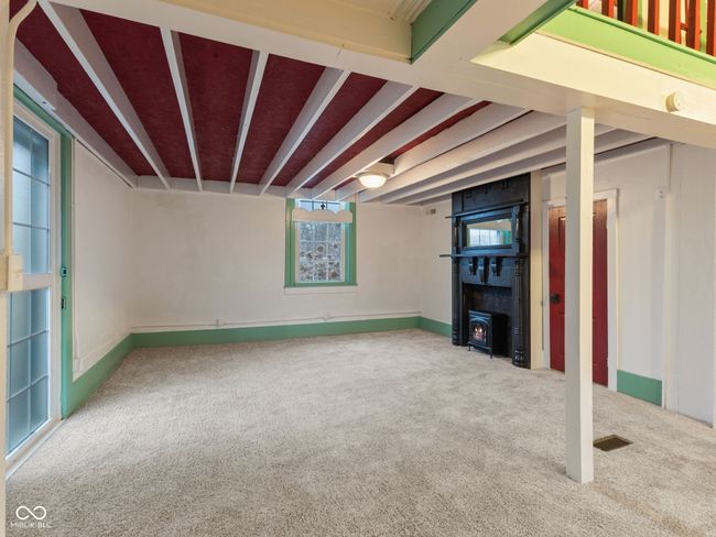 below grade area with plenty of natural light, visible vents, carpet floors, and a wood stove | Image 5