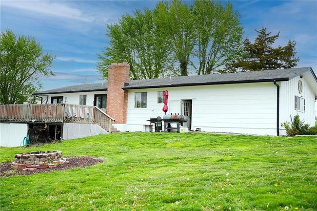 Back of property with a wooden deck, a chimney, an outdoor fire pit, stairway, and a yard | Image 4