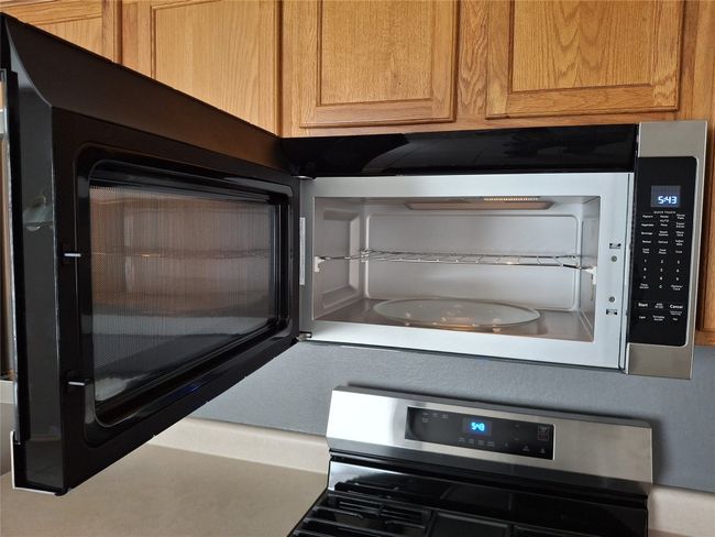 Kitchen view of stainless steel gas stove and new microwave | Image 18