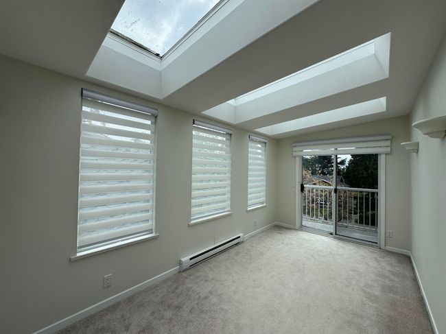 Unfurnished room featuring a baseboard heating unit, carpet, a skylight, and baseboards | Image 10