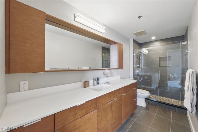 Bathroom featuring toilet, vanity, tile patterned floors, and a stall shower | Image 23