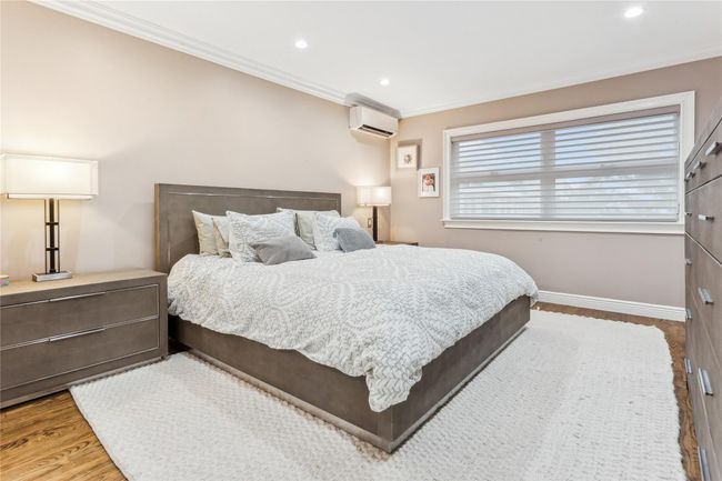 Bedroom with ornamental molding, a wall mounted air conditioner, and wood-type flooring | Image 10
