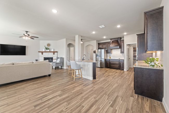 Kitchen featuring arched walkways, dark wood cabinets, a ceiling fan, open floor plan, and recessed lighting. | Image 12