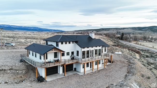 Rear view of property featuring a chimney, driveway, an attached garage, and metal roof | Image 33