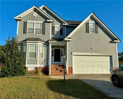 View of property with a front yard and a garage | Image 1