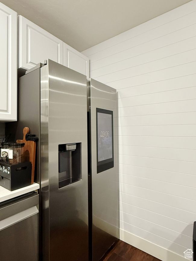 Kitchen featuring stainless steel refrigerator with ice dispenser, dark wood finished floors, and white cabinetry | Image 5