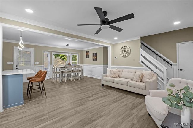 Living area with a wainscoted wall, a decorative wall, stairway, crown molding, and light wood finished floors | Image 14