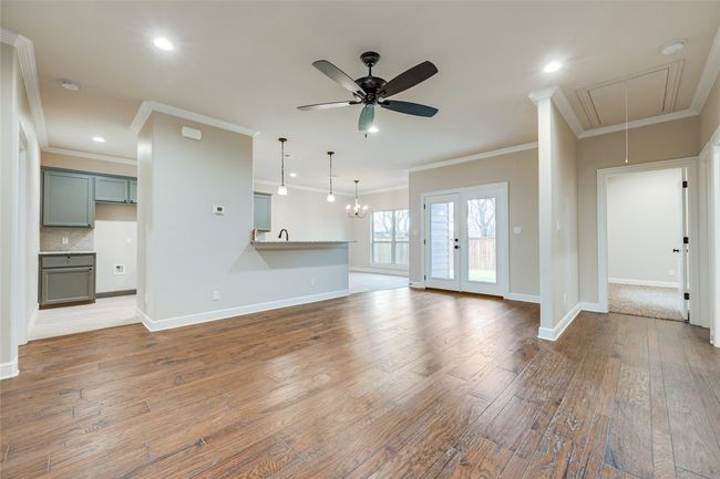 Unfurnished living room featuring attic access, ornamental molding, ceiling fan, hardwood / wood-style floors, and baseboards | Image 4