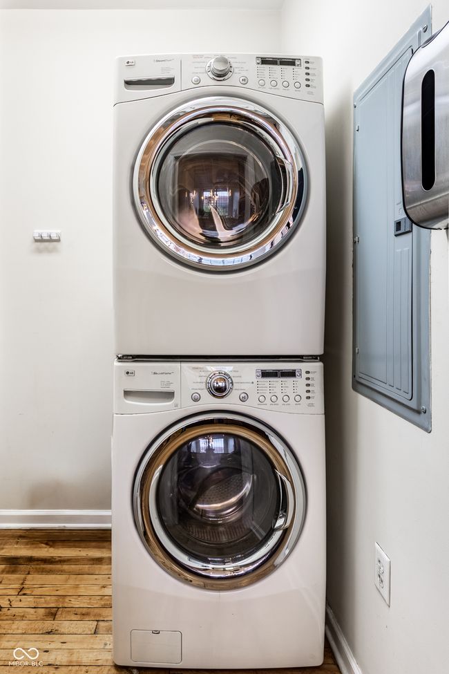 laundry area with stacked washer / dryer and wood finished floors | Image 29