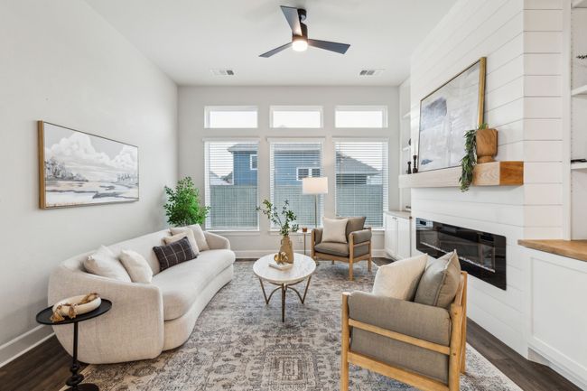 Living room with dark wood finished floors, ceiling fan, a glass covered fireplace, and baseboards | Image 8