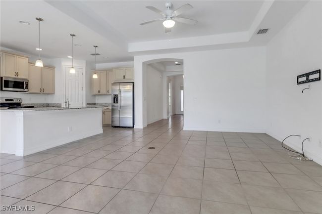 Kitchen featuring stainless steel appliances, arched walkways, cream cabinetry, ceiling fan, and light tile patterned floors | Image 20