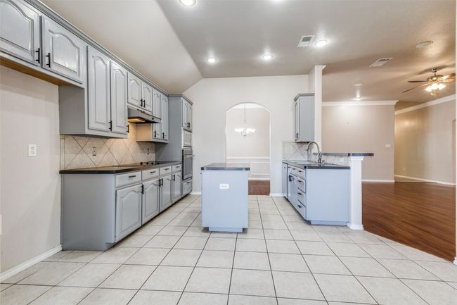 Kitchen featuring dark countertops, tasteful backsplash, a center island, gray cabinets, and ornamental molding | Image 13