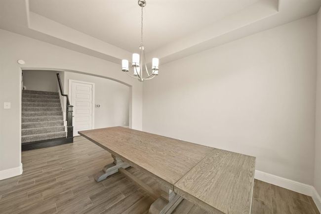 Formal dining room with tray ceiling and modern lighting—perfect for hosting unforgettable dinners and celebrations | Image 6