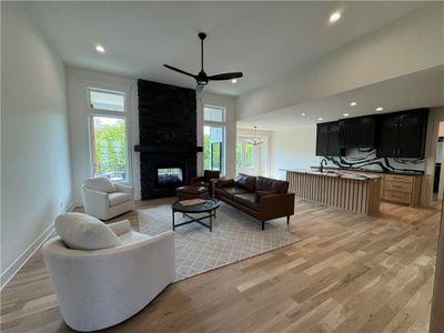 Living room with ceiling fan with notable chandelier, a multi sided fireplace, and light hardwood / wood-style floors | Image 2