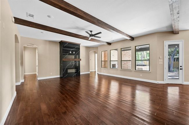 Unfurnished living room with arched walkways, baseboards, visible vents, and hardwood / wood-style floors | Image 38