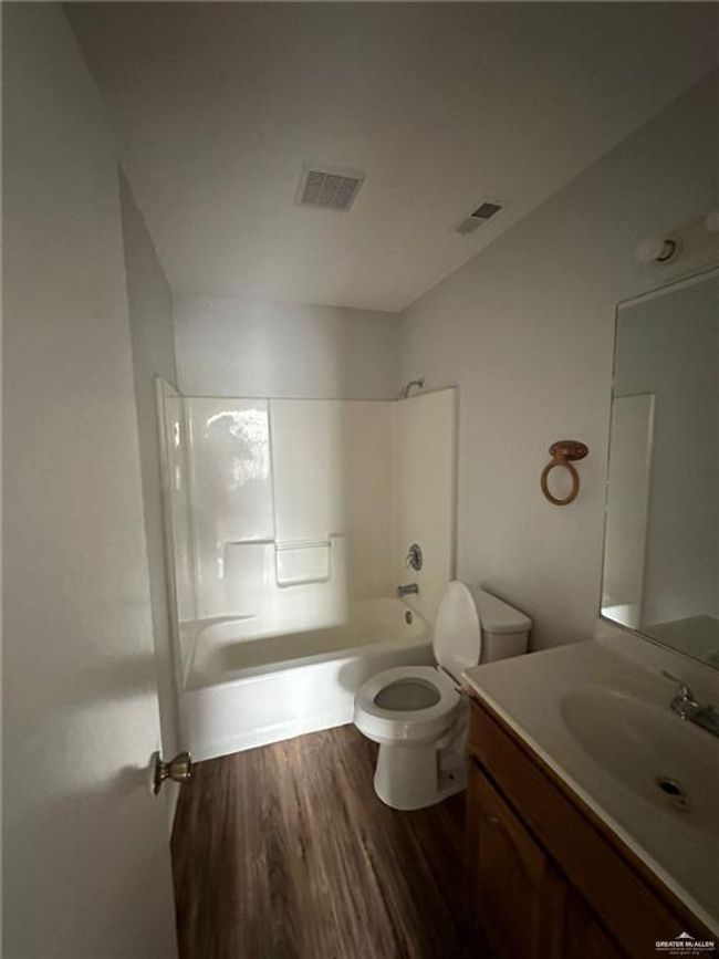 Full bathroom featuring visible vents, toilet, shower combination, and wood finished floors | Image 6