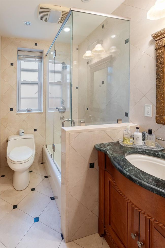 Bathroom with tile walls, vanity, tile patterned flooring, and shower / bath combination with glass door | Image 11