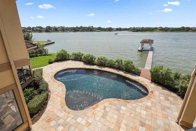 This view is from the Flex room showcasing the private pool and lakeside location. The view includes a dock extending into the water, perfect for boating or relaxing. The lush green landscaping adds to the serene and picturesque setting. | Image 30