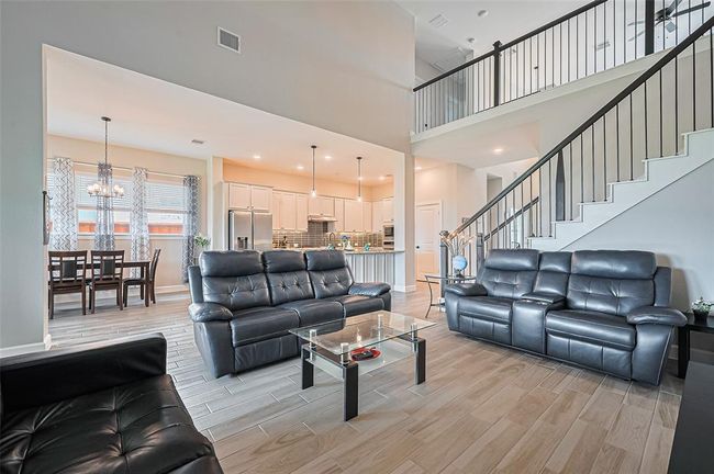 Expansive living room with soaring ceilings, large windows for natural light, and open access to the kitchen and dining—perfect for entertaining | Image 6
