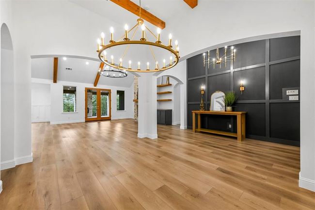 Unfurnished living room featuring beamed ceiling, light hardwood / wood-style flooring, high vaulted ceiling, and an inviting chandelier | Image 5