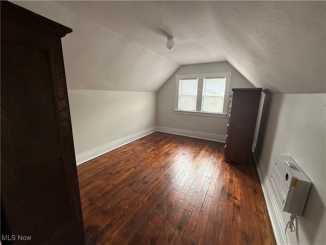 Additional living space with dark wood-style flooring, a wall unit AC, vaulted ceiling, baseboards, and a textured ceiling | Image 8