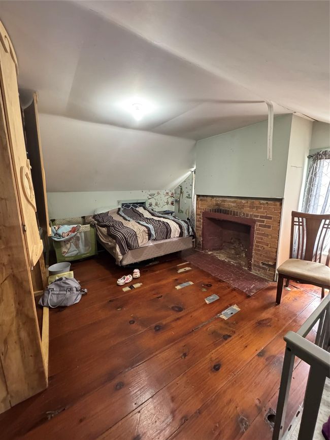 Bedroom featuring vaulted ceiling, a brick fireplace, and hardwood / wood-style floors | Image 22