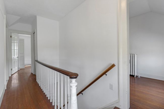 Stairs with radiator, hardwood / wood-style floors, vaulted ceiling, and baseboards | Image 33